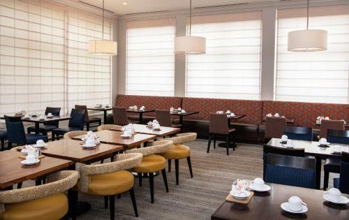 a dining room with tables and chairs and windows at Hilton Garden Inn BWI Airport in Linthicum Heights