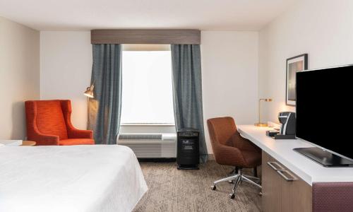 a hotel room with a bed and a desk with a computer at Hilton Garden Inn BWI Airport in Linthicum Heights