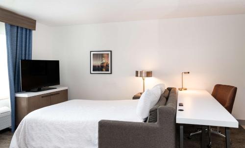 a hotel room with a bed and a couch and a tv at Hilton Garden Inn BWI Airport in Linthicum Heights