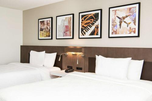 two beds in a hotel room with framed pictures on the wall at Hilton Garden Inn BWI Airport in Linthicum Heights
