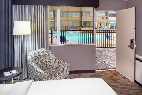 a hotel room with a bed and a chair and a pool at DoubleTree by Hilton Cleveland – Westlake in Westlake