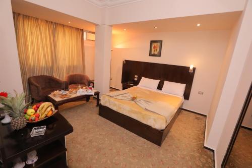 Swiss Inn Hotel Mohandeseen في القاهرة: غرفة فندق مع غرفة نوم مع سرير وكرسي