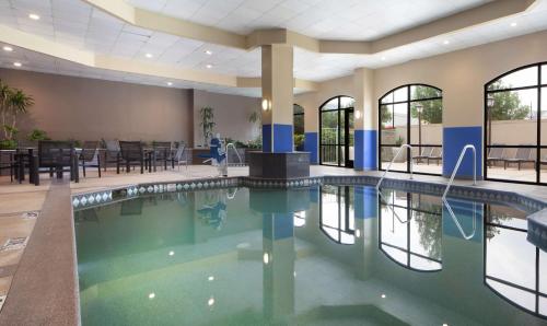 a pool in the lobby of a hotel with tables and chairs at Embassy Suites by Hilton Dallas Near the Galleria in Dallas