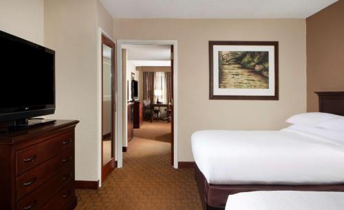 a hotel room with a bed and a flat screen tv at Embassy Suites by Hilton Dallas Near the Galleria in Dallas
