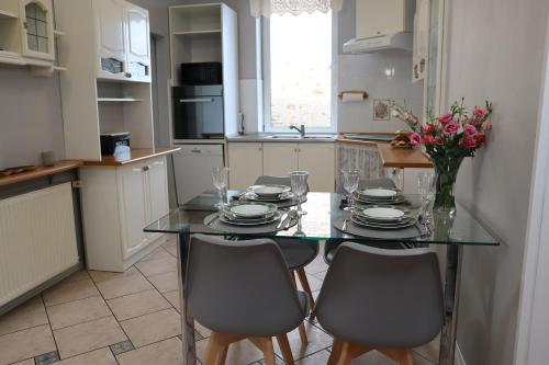 una cocina con una mesa de cristal con sillas y flores en Apartament w kamienicy, en Ostróda