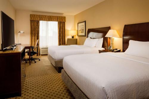 a hotel room with two beds and a desk at Hilton Garden Inn Cincinnati Blue Ash in Blue Ash