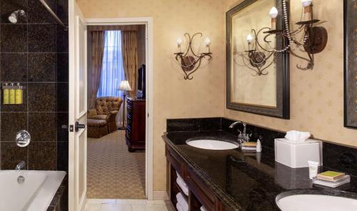 ein Badezimmer mit zwei Waschbecken, einer Badewanne und einem Spiegel in der Unterkunft Hilton Fort Worth in Fort Worth