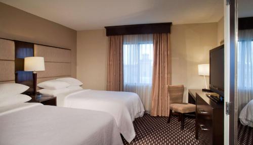 a hotel room with two beds and a television at Embassy Suites by Hilton Houston Near the Galleria in Houston