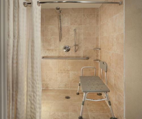 a shower with a chair in a bathroom at Embassy Suites by Hilton Houston Near the Galleria in Houston