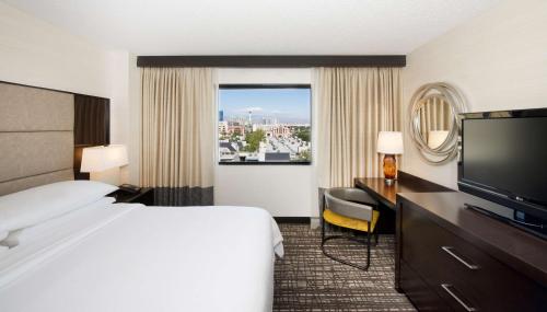 a hotel room with a bed and a flat screen tv at Embassy Suites by Hilton Las Vegas in Las Vegas