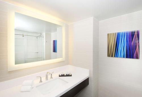 a bathroom with a sink and a painting on the wall at Embassy Suites by Hilton Las Vegas in Las Vegas