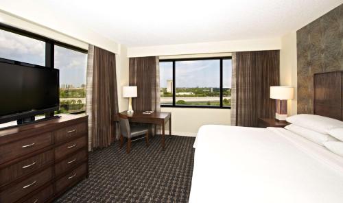 a hotel room with a bed and a flat screen tv at Embassy Suites by Hilton Palm Beach Gardens PGA Boulevard in Palm Beach Gardens