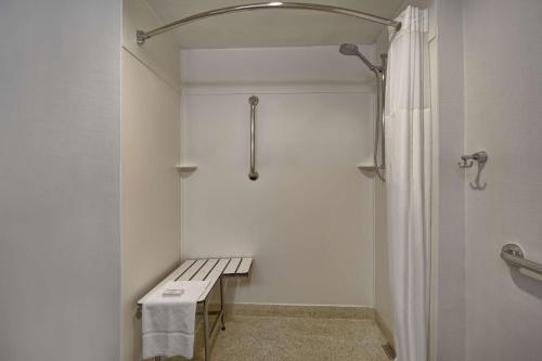 a white bathroom with a bench and a shower at Hampton Inn NY-JFK in Queens