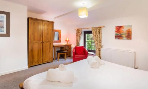 a bedroom with two white beds and a red chair at Old Barn Cottage in Newby Bridge