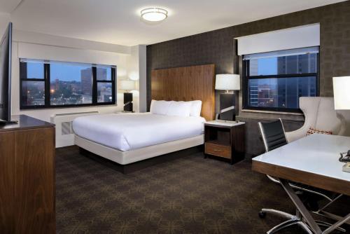 ein Hotelzimmer mit einem Bett, einem Schreibtisch und 2 Fenstern in der Unterkunft DoubleTree by Hilton Hotel & Suites Pittsburgh Downtown in Pittsburgh