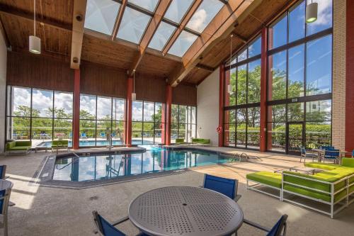 una gran piscina cubierta con mesa, sillas y ventanas en DoubleTree by Hilton Pittsburgh - Cranberry, en Cranberry Township