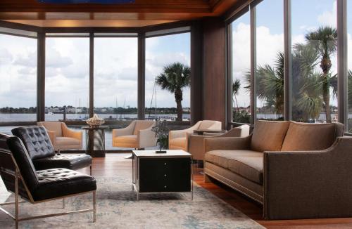 a living room with couches and chairs and windows at Hilton Houston NASA Clear Lake in Seabrook