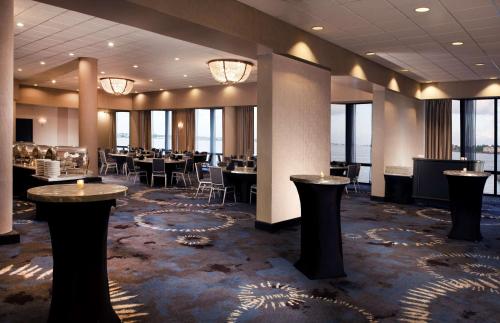 a dining room with tables and chairs and windows at Hilton Houston NASA Clear Lake in Seabrook