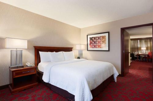 a hotel room with a large bed with white sheets at Embassy Suites by Hilton Dulles Airport in Herndon