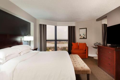 a bedroom with a large white bed and a chair at Hilton Houston NASA Clear Lake in Seabrook