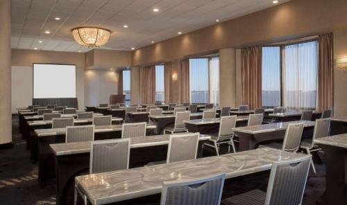 a conference room with tables and chairs and windows at Hilton Houston NASA Clear Lake in Seabrook