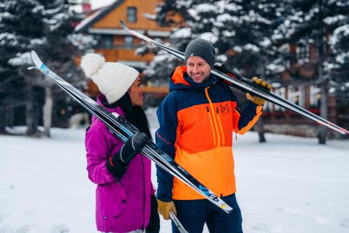 een man en een vrouw die ski's in de sneeuw houden bij Post Hotel & Spa in Lake Louise