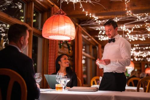 een man die voor een tafel staat in een restaurant bij Post Hotel & Spa in Lake Louise