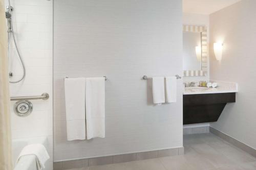 y baño con ducha, toallas blancas y lavamanos. en DoubleTree by Hilton Hotel Syracuse, en East Syracuse