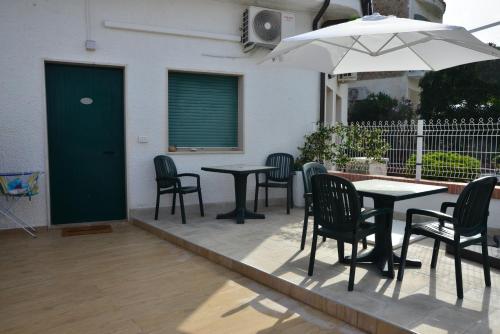 eine Terrasse mit Tischen, Stühlen und einem Sonnenschirm in der Unterkunft Residence Airone in Termoli