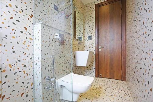 La salle de bains est pourvue de toilettes et d'une douche en verre. dans l'établissement Frankstay By Hotel Preet in 05 mints walking Distance Nizamuddin Railway Station, à New Delhi
