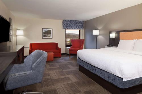 a hotel room with a bed and a chair at Hampton Inn Charleston-Southridge in Charleston