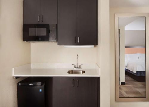 a kitchen with black cabinets and a sink at Hampton Inn Charleston-Southridge in Charleston
