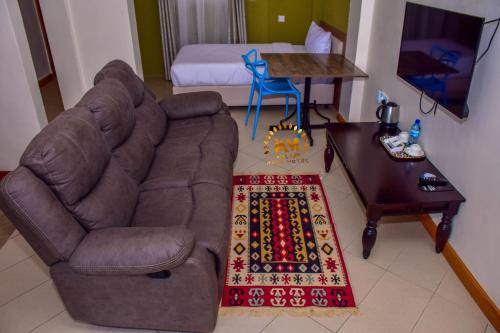 uma sala de estar com um sofá, uma mesa e uma cama em Walabi Mara Hotel em Narok