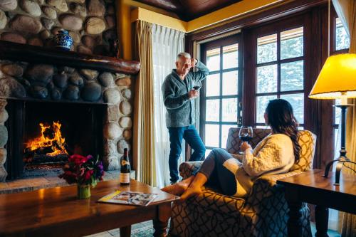 a man standing in a living room next to a fireplace at Post Hotel & Spa in Lake Louise