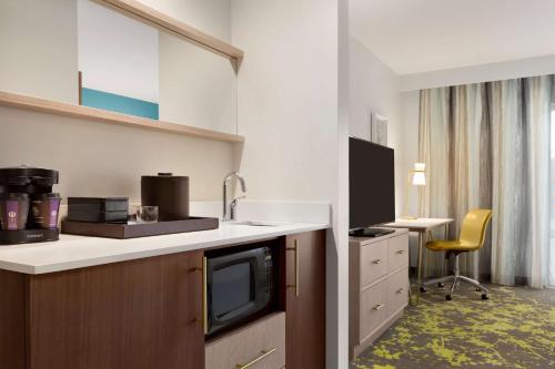 a hotel room with a kitchen with a sink and a desk at Embassy Suites By Hilton Boulder in Boulder