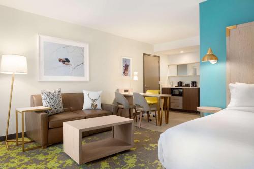 a hotel room with a bed and a couch and a table at Embassy Suites By Hilton Boulder in Boulder