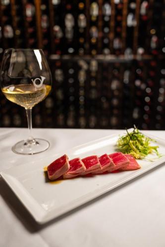 a white plate with meat and a glass of wine at Post Hotel & Spa in Lake Louise