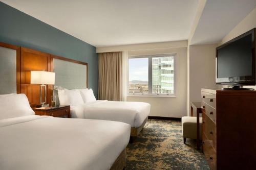 a hotel room with two beds and a flat screen tv at Embassy Suites by Hilton Denver Downtown Convention Center in Denver