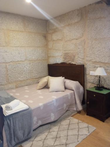 a bedroom with a bed and a brick wall at O Noso Lar - RIBEIRA SACRA in Nogueira de Ramuin