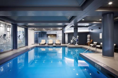 a large swimming pool with blue water in a building at The Logan Philadelphia, Curio Collection by Hilton in Philadelphia