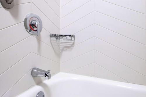 a white bathroom with a sink and a faucet at Joinery Hotel Pittsburgh, Curio Collection by Hilton in Pittsburgh