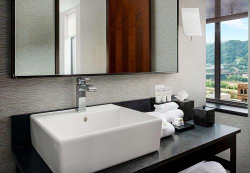 a bathroom with a white sink and a mirror at Joinery Hotel Pittsburgh, Curio Collection by Hilton in Pittsburgh