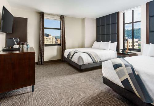 a hotel room with two beds and a television at Joinery Hotel Pittsburgh, Curio Collection by Hilton in Pittsburgh