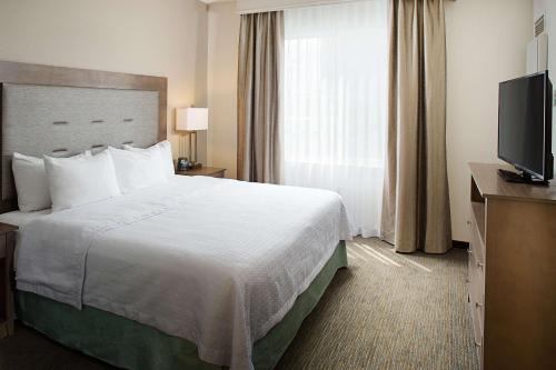 a hotel room with a bed and a television at Homewood Suites by Hilton Albuquerque Uptown in Albuquerque