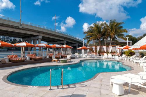 a swimming pool with lounge chairs and umbrellas at Waterstone Resort & Marina Boca Raton, Curio Collection by Hilton in Boca Raton