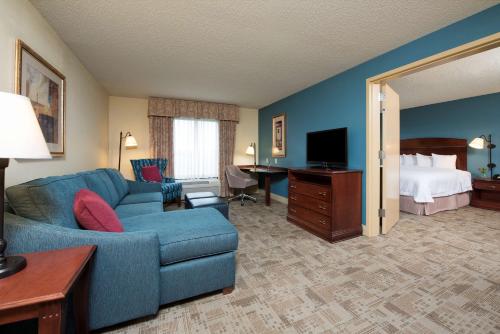a living room with a blue couch and a bed at Hampton Inn & Suites Bloomington-Normal in Normal