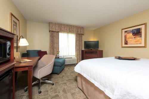 a hotel room with a bed and a desk and a television at Hampton Inn & Suites Bloomington-Normal in Normal