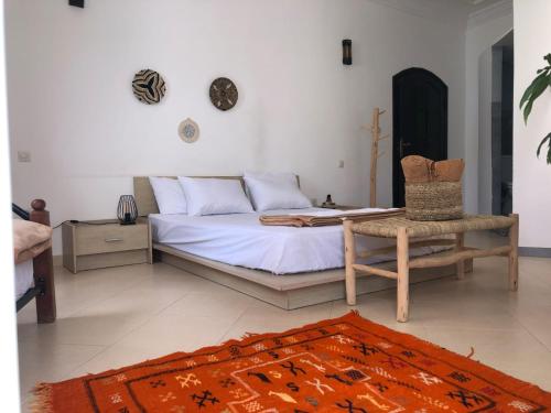een slaapkamer met een bed, een stoel en een tapijt bij Arima Surf House in Tamraght Ouzdar