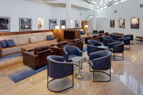 un salone con sala d'attesa con sedie blu di Hilton Nashville Airport a Nashville