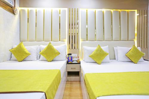 two beds in a hotel room with yellow and white pillows at Hotel Preet Palace -5 Mints Walk From Nizamuddin Railway Station in New Delhi